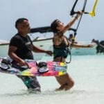 Mężczyzna pomaga kobiecie w nauce kitesurfingu na słonecznej plaży