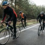 Trzech rowerzystów jedzie leśną drogą w ciągu dnia