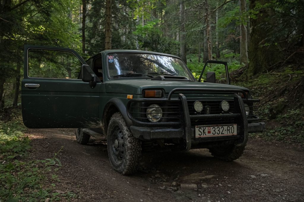 Zielony SUV zaparkowany na wyboistej leśnej drodze